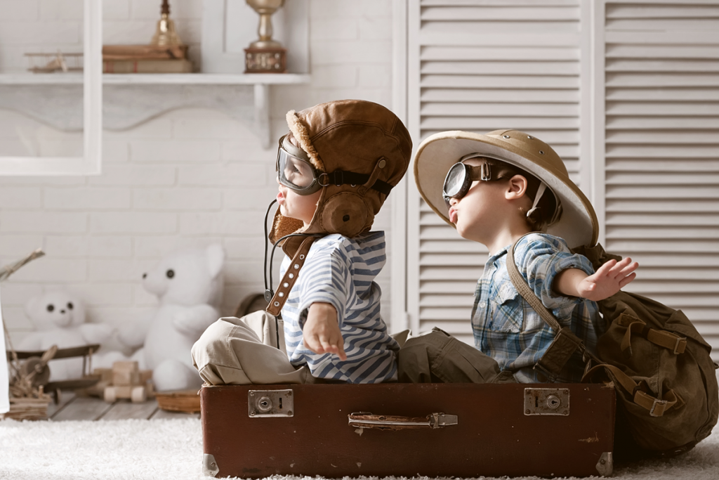 boys pretending to fly in suitcase